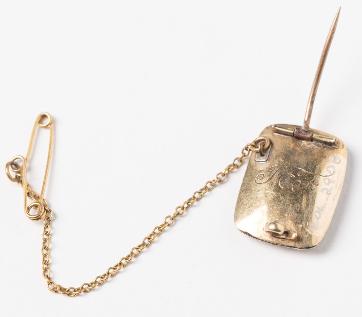 The back of a gold mourning brooch: a long pin on a hinge, and a fine chain with a small safety pin.
